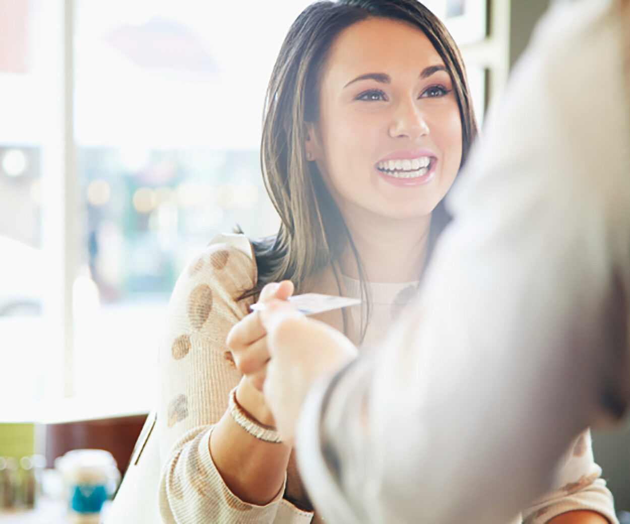 woman smiling and handing a credit card to a cashier